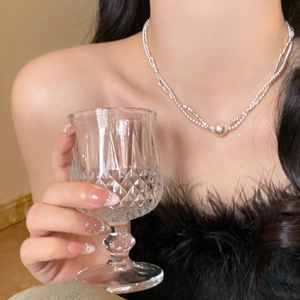 Close-up of elegant double-layer silver pearl necklace worn by a model in soft lighting