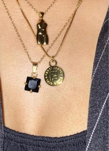 Dettaglio di collane d'oro a strati con ciondolo in zircone nero e ciondoli artistici