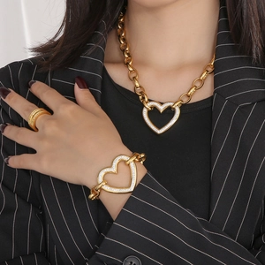 Macro detail of gold chunky chain jewelry set with sparkling heart pendants on a model