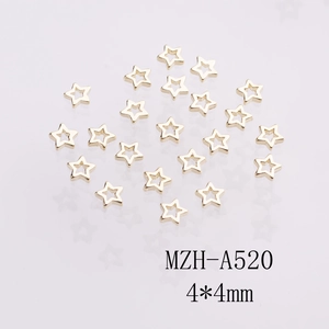 Macro view of 4x4mm golden alloy hollow star nail art charms on a gray reflective surface