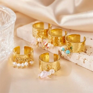 Detailed close-up of textured gold open rings with natural stones and pearls on silk