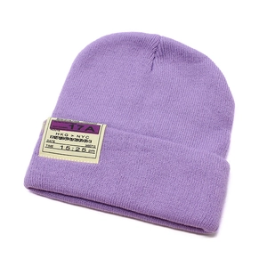 Detail of a purple knitted beanie featuring a creative boarding pass style fabric label