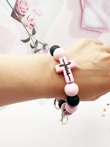 Detailed shot of pink and black silicone bead bracelet with Jesus cross on a wrist