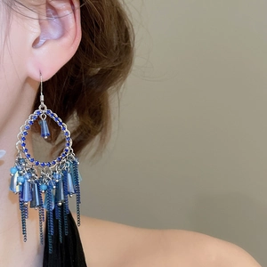 Close-up of bohemian blue crystal fringe earrings with long metal chain tassels