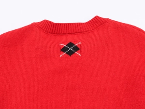 Close-up of red knit sweater featuring black and white diamond pattern at the neckline