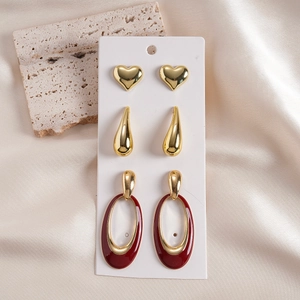 Detailed set of golden heart and teardrop earrings with red enamel on a display card