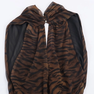 Détail d'une robe en mousseline imprimé tigre avec boutons métalliques argentés