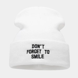 Detailed close-up of white knitted beanie with black embroidery text slogan