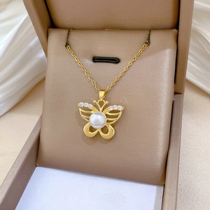Close-up of golden butterfly pendant with pearls and crystals in a jewelry box