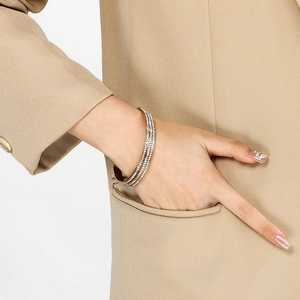 Close-up of three stacked gold-plated bangle bracelets with pave diamond settings