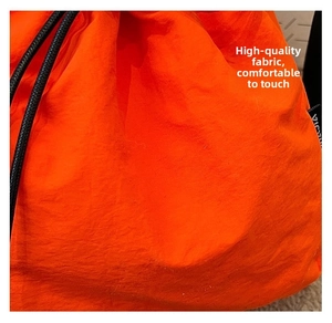 Detailed close-up of vibrant orange nylon fabric with drawstring and woven label