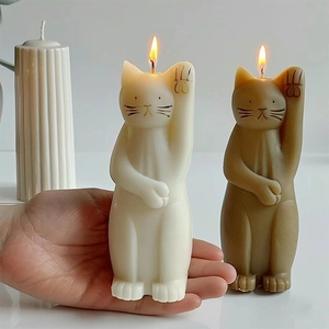 Vela aromática gato de la suerte en crema y marrón sostenida en la mano para escala