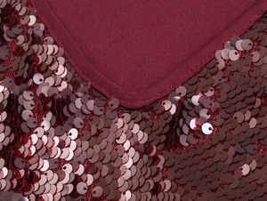 Dettaglio vestito rosso scuro con paillettes che mostra scollo a V e tessuto di lusso
