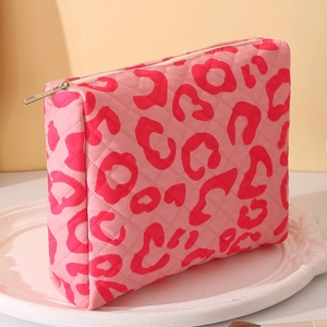 Pink leopard print quilted makeup bag with zipper closure on a white decorative plate