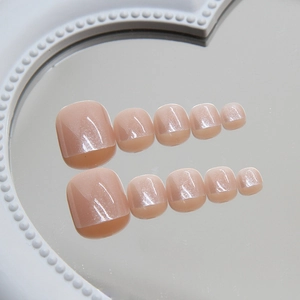 Glossy nude pink press-on toe nails with cat eye glitter effect on a heart tray