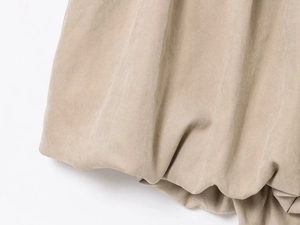 Gros plan sur la texture du tissu beige et les détails de couture de la mini-jupe ballon