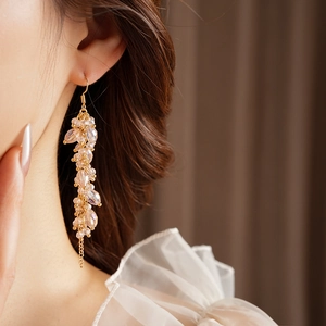Close-up of bohemian pink crystal tassel earrings with gold-tone hooks on a model