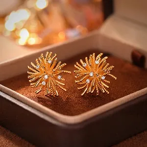 Close-up of golden starburst stud earrings with white cubic zirconia in a velvet box