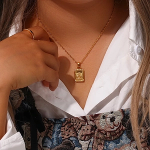 Close-up of a gold angel relief pendant on a twisted chain necklace worn by a model