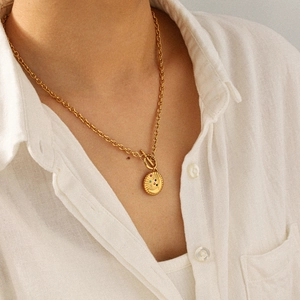 Détail du collier doré avec fermoir OT et pendentif lune étoile orné de gemmes colorées