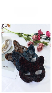 Detailed view of ornate cat face masquerade masks in red, blue, and gold with floral accents
