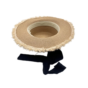 Detailed close-up of woven straw texture and stylish frayed edge on a wide brim sun hat