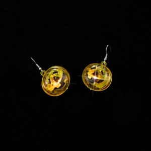Macro shot of glowing yellow pumpkin earrings with internal LED lights and hook design