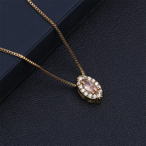Close-up of a gold teardrop pendant with champagne zircon and white crystals on black leather