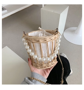 Detail of hand-woven straw bucket bag with large pearl handle and white drawstring liner