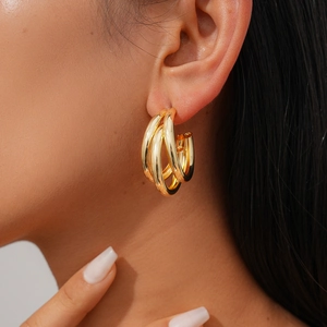 Modern gold triple-layered hoop earrings worn by a model in a high-quality close-up shot