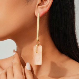 Detail of pink marble resin pendant and golden bar on elegant dangling earrings for women