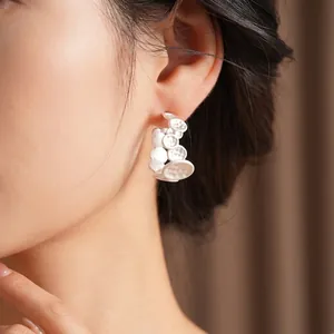 Minimalist white C-shaped irregular earrings with textured dotted pattern worn by model