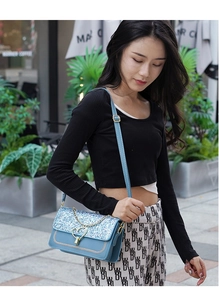 Blue sequin handbag with chain strap and heart lock shown in an outdoor street style