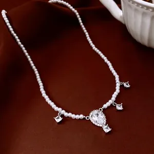 Elegant pearl necklace featuring a teardrop pendant on a premium red velvet background