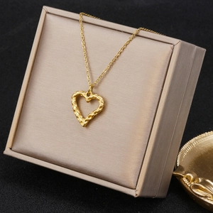 Detail of golden heart necklace with hammer texture in a beige satin display box