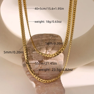 Golden flat cuban chain necklaces in 5mm width shown in two lengths on stone stand