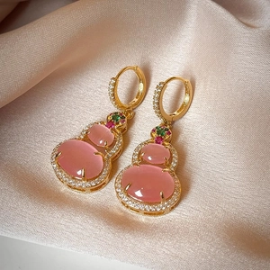Macro view of 14k gold plated pink cat-eye stone gourd earrings with silk background