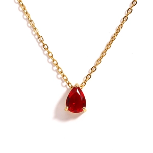Detail of gold necklace with a red pear-shaped zircon teardrop birthstone pendant