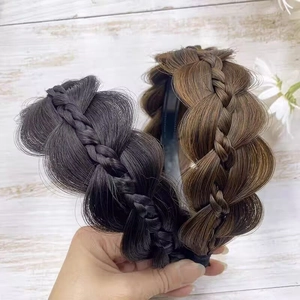 Detail of fishtail braid hairbands in black and dark brown on a wood background