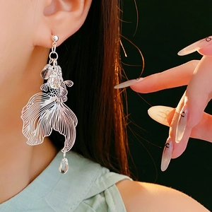 Macro side view of silver koi fish earrings with crystal beads on a model profile