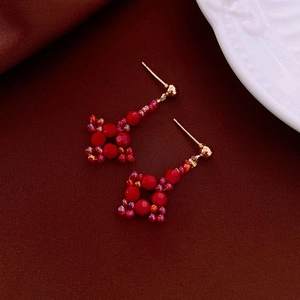 Gros plan détaillé de boucles d'oreilles artisanales en perles rouges facettées