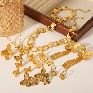 Close-up of golden butterfly jewelry set including necklace, bracelet and ring on wood