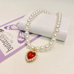 Close-up of pearl necklace featuring a red heart pendant with small pearl trim
