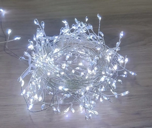 Detail view of cold white LED copper wire fairy lights on a rustic wooden table surface