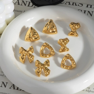 Detailansicht goldener geometrischer Dreiecks- und Schmetterlingsohrringe auf Keramikteller