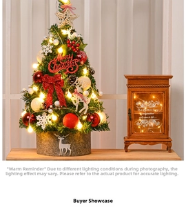 Mini lighted Christmas tree with red bows, ornaments, and LED lights on a wooden table