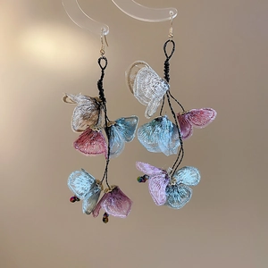 Detailed view of floral fabric tassel earrings with intricate embroidery and blue petals