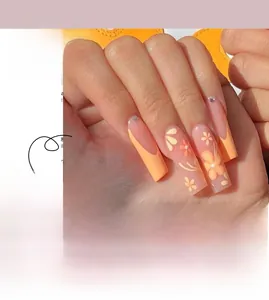 Detailed view of orange French press-on nails with yellow floral patterns and small rhinestones