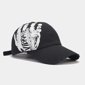 Detail of street style black cotton baseball cap with white graffiti print and distressed brim