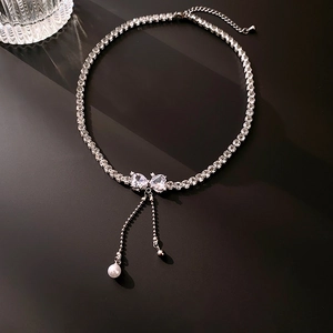 Macro detail of silver zircon bow necklace with hanging pearl and adjustable chain